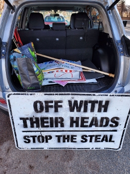 open hatchback of car with sign propped against it reading