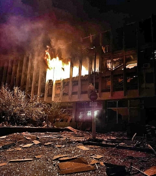 exterior of library building in flames with debris on ground
