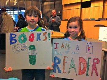 young boy and girl at advocacy rally holding up homemade pro-reading signs